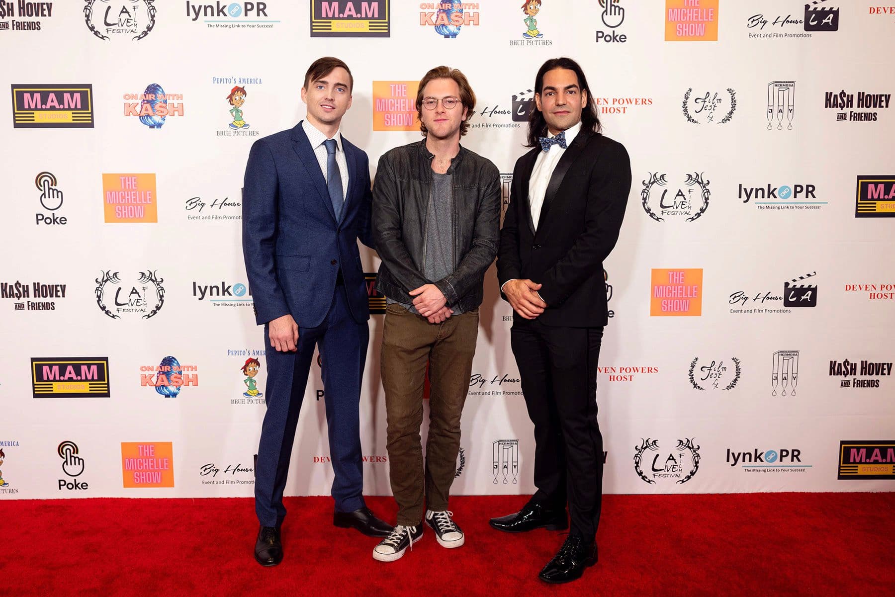 Artem Shestakov, Quinn Halleck and David Runyon posing on a red carpet, dressed in formal attire at Los Angeles film festival.