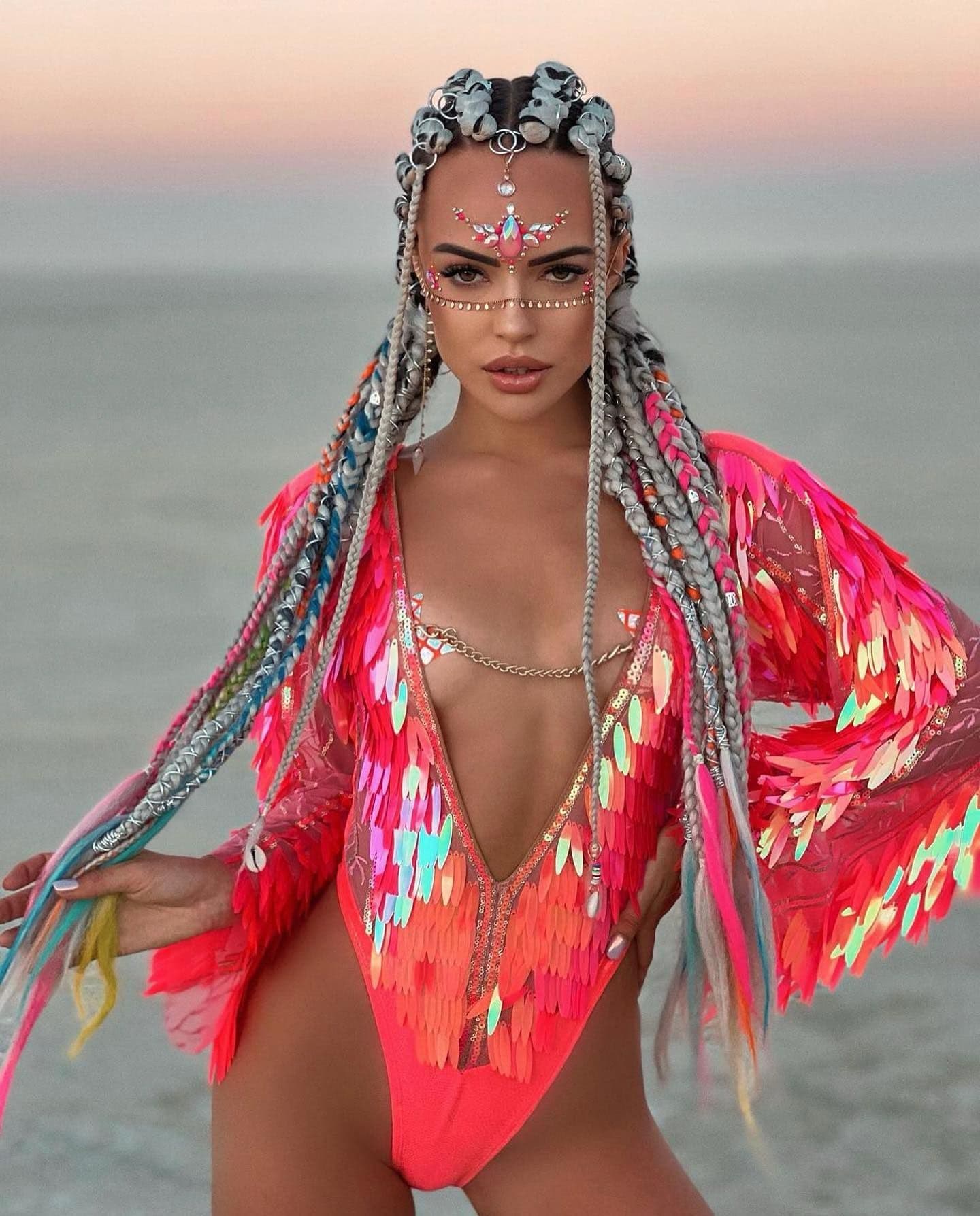 A person with elaborate festival braids and a colorful sequined outfit at Burning Man.