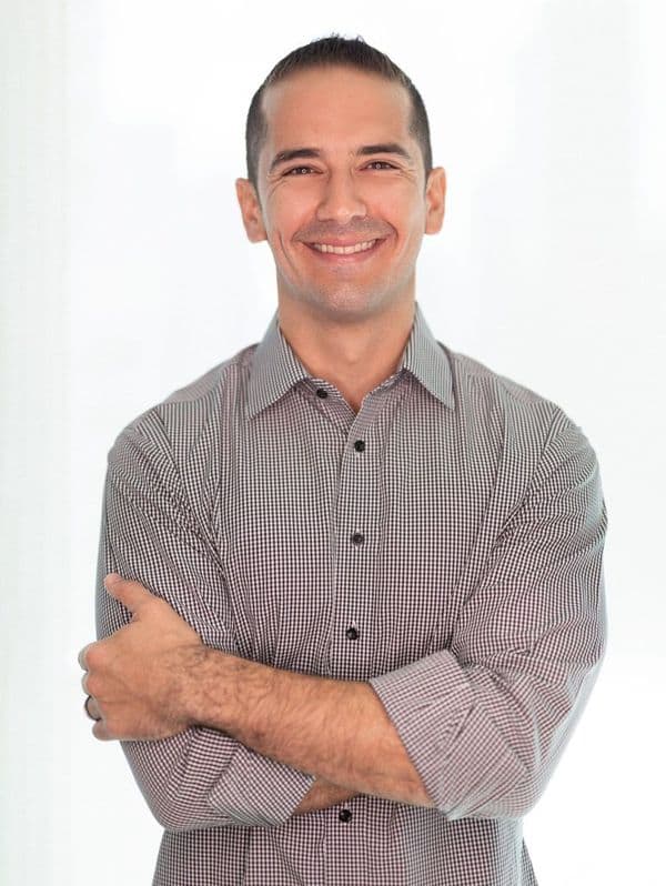Smiling headshot of Alex Arguelles in a checkered shirt with arms crossed.