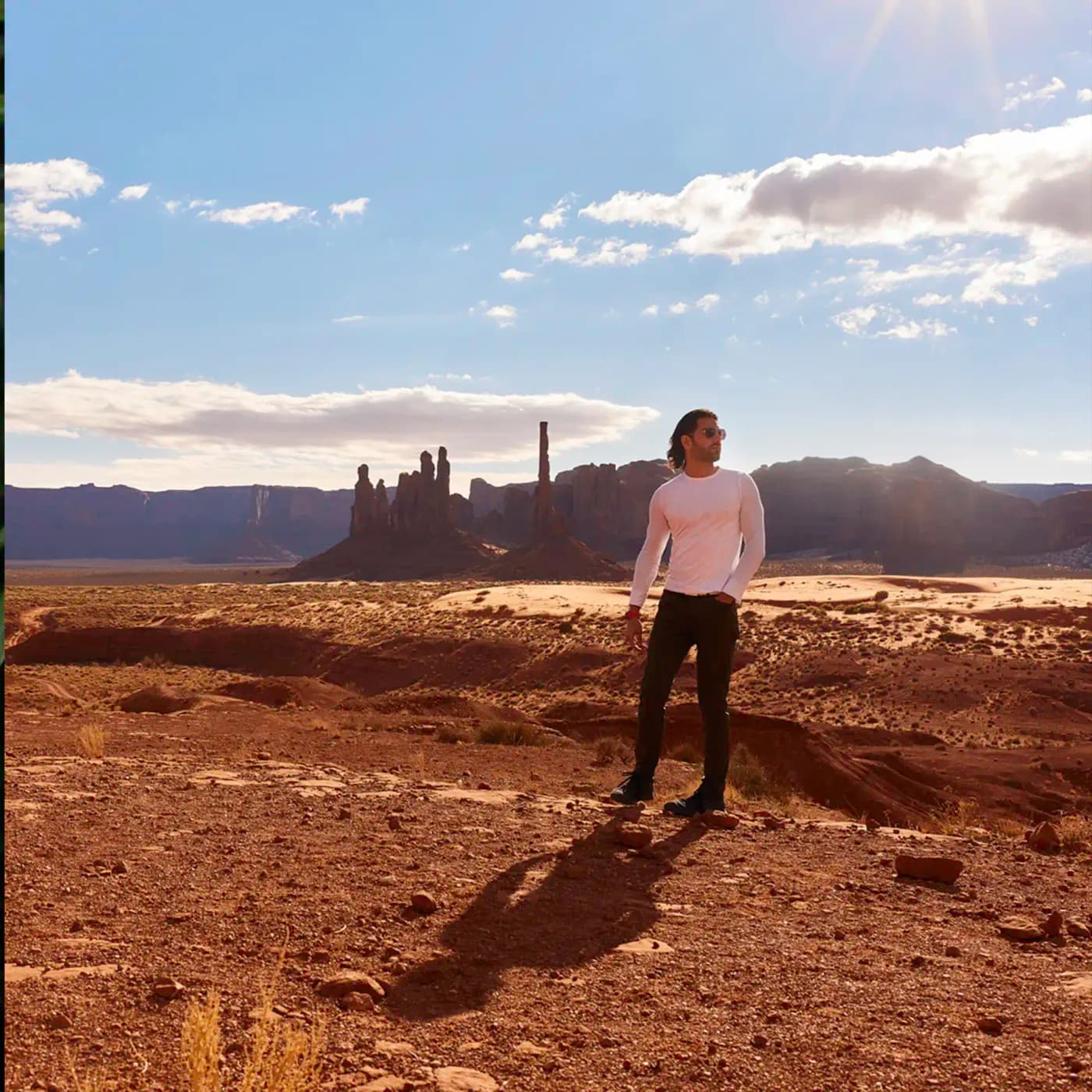 David Runyon standing in an Arizona desert wearing tight fitting long white shirt and green pants.