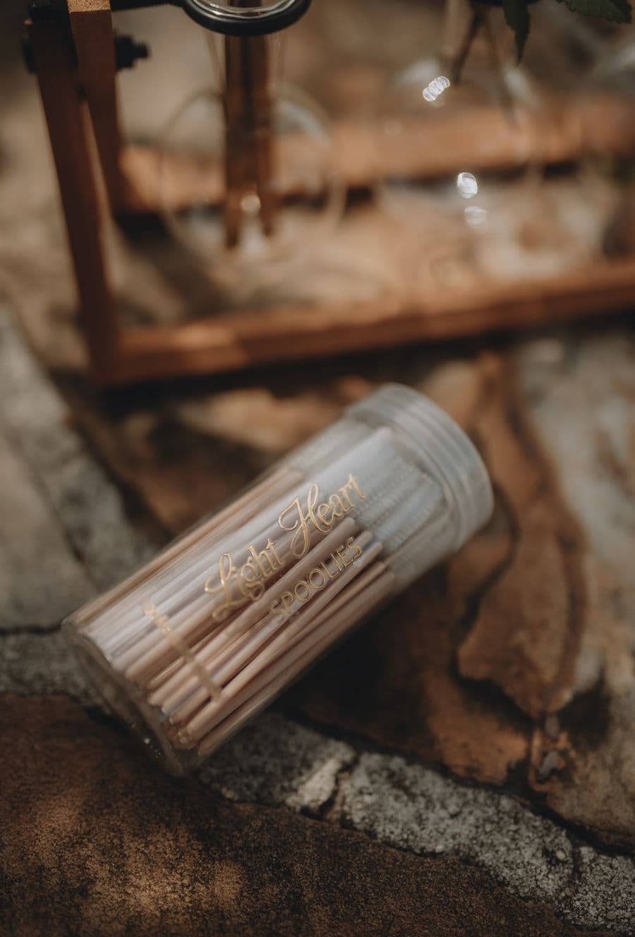 A clear container labeled Light Heart Spoolies filled with makeup brushes on a stone surface, showcasing a makeup artist's professional tools for a visual portfolio.