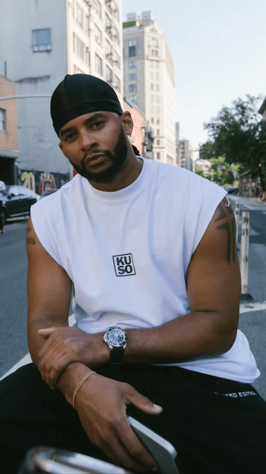 Creative director Mike Press wearing a black durag and white t-shirt, sitting on an NYC street.