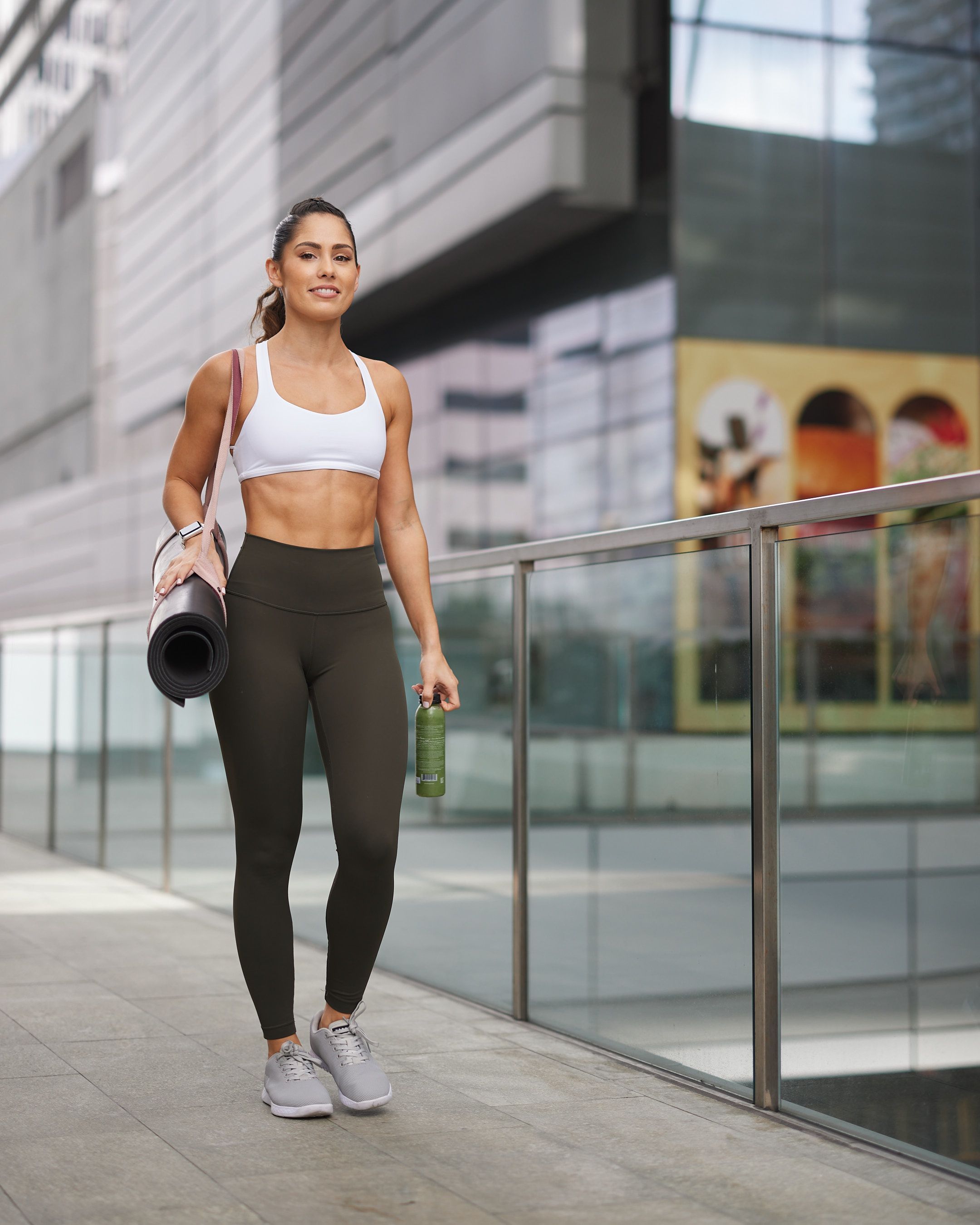 Valerie Senior walks in Brickell City Center with a yoga mat and smoothie, dressed in athletic wear.