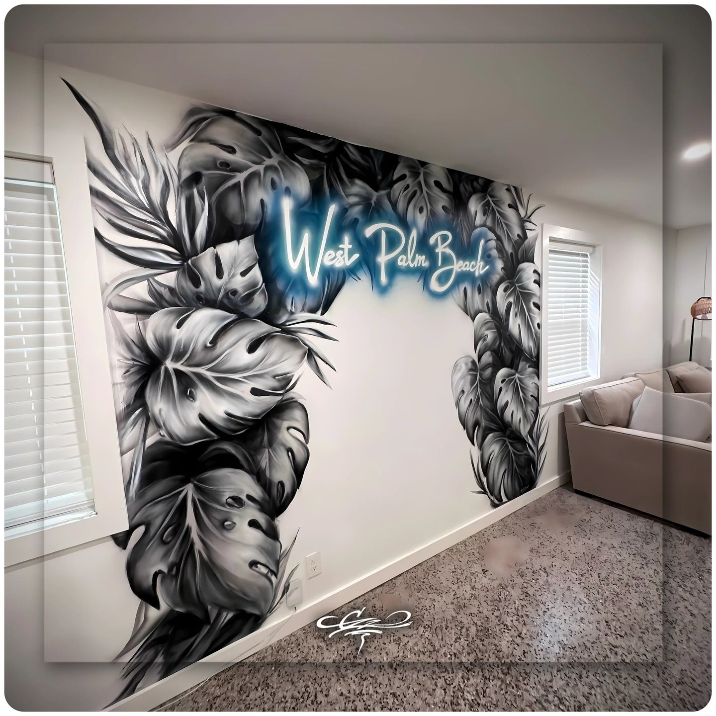 A custom wall mural of black-and-white tropical leaves framing 'West Palm Beach' in a blue, neon-style script.