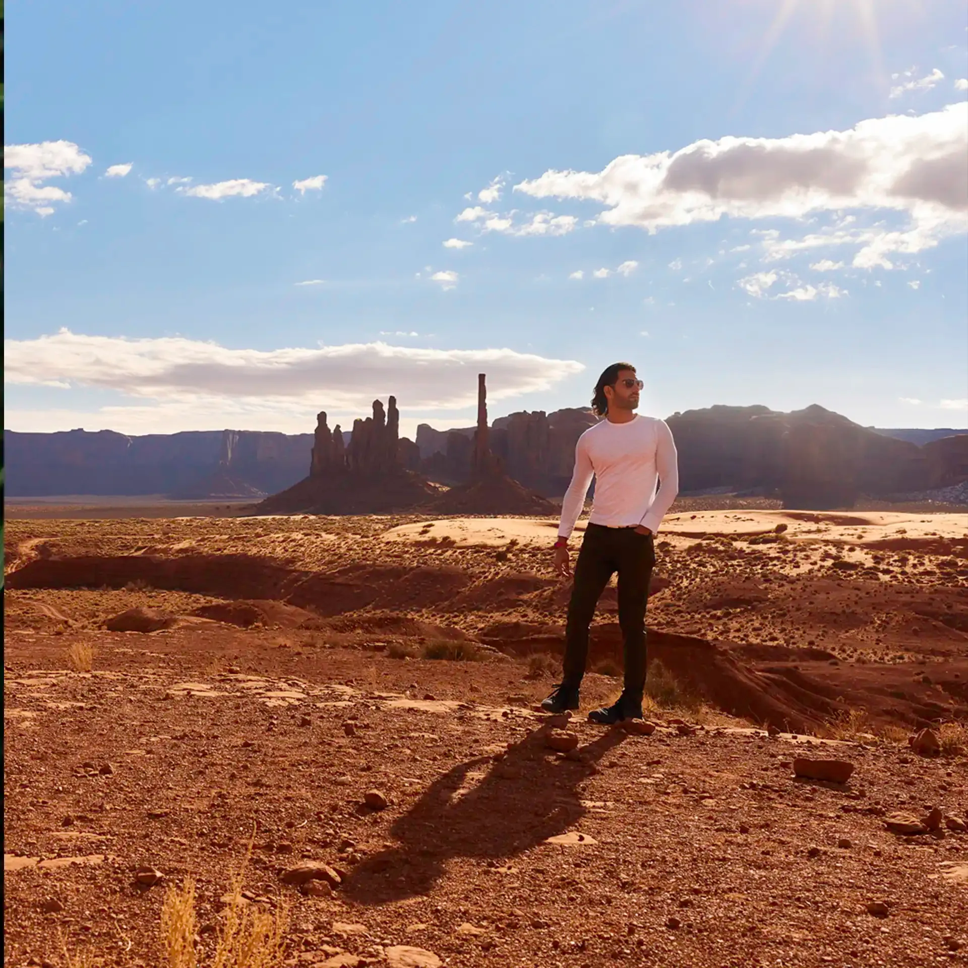 David Runyon standing in an Arizona desert wearing tight fitting long white shirt and green pants.