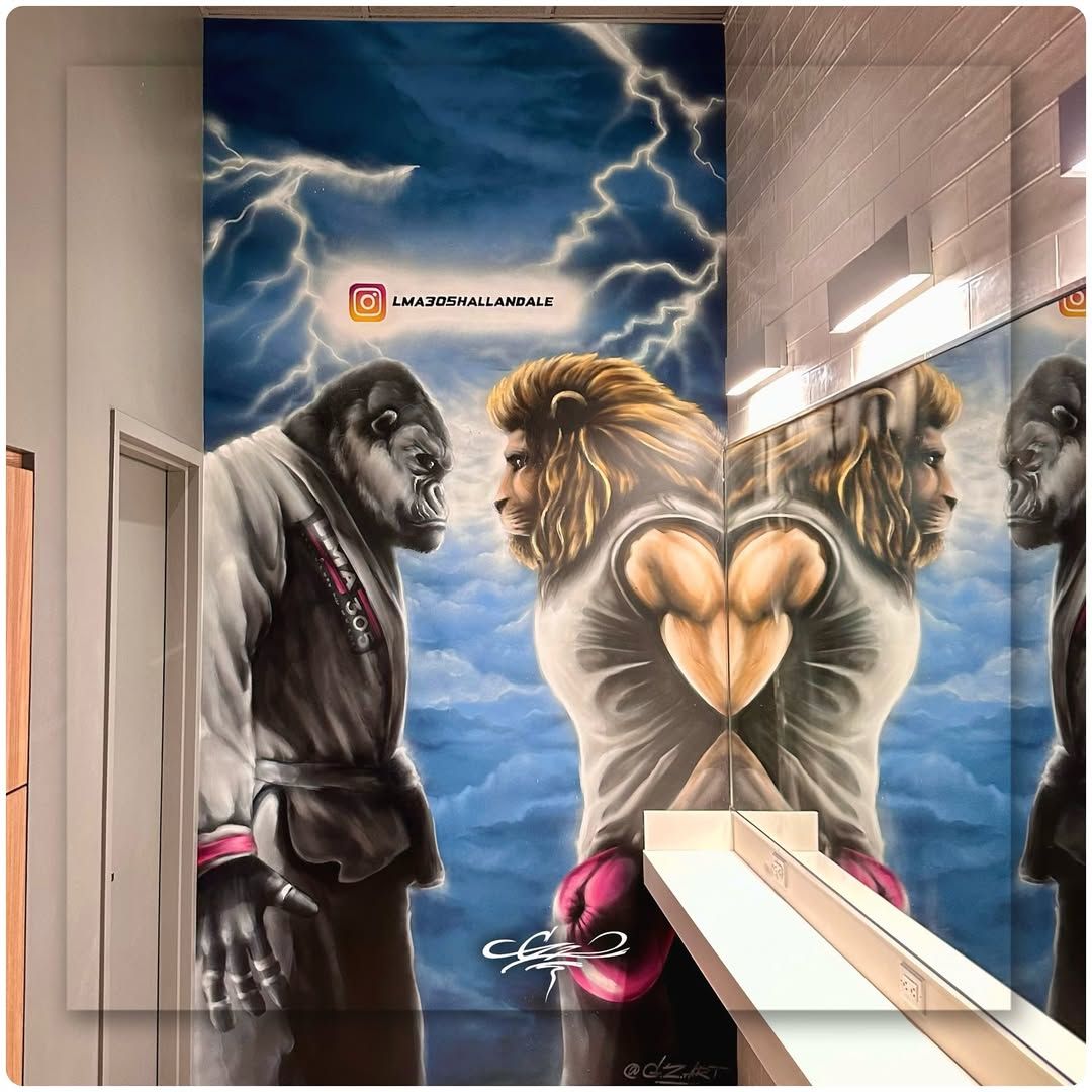 Custom commercial mural of a gorilla in a martial arts gi facing a lion in boxing gloves under a stormy sky.