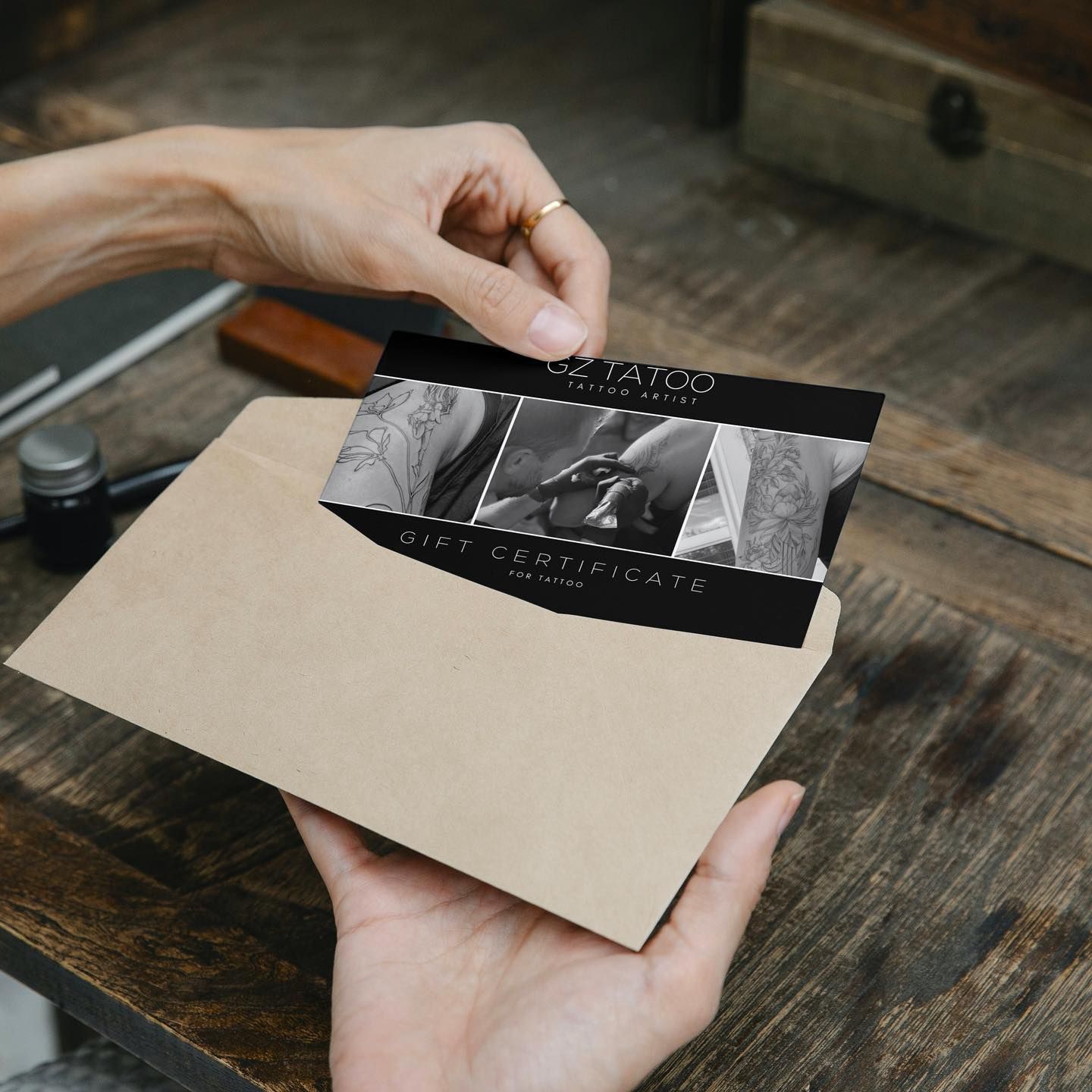 A potential client pulling a GZ Tattoo gift certificate out of a brown paper envelope.