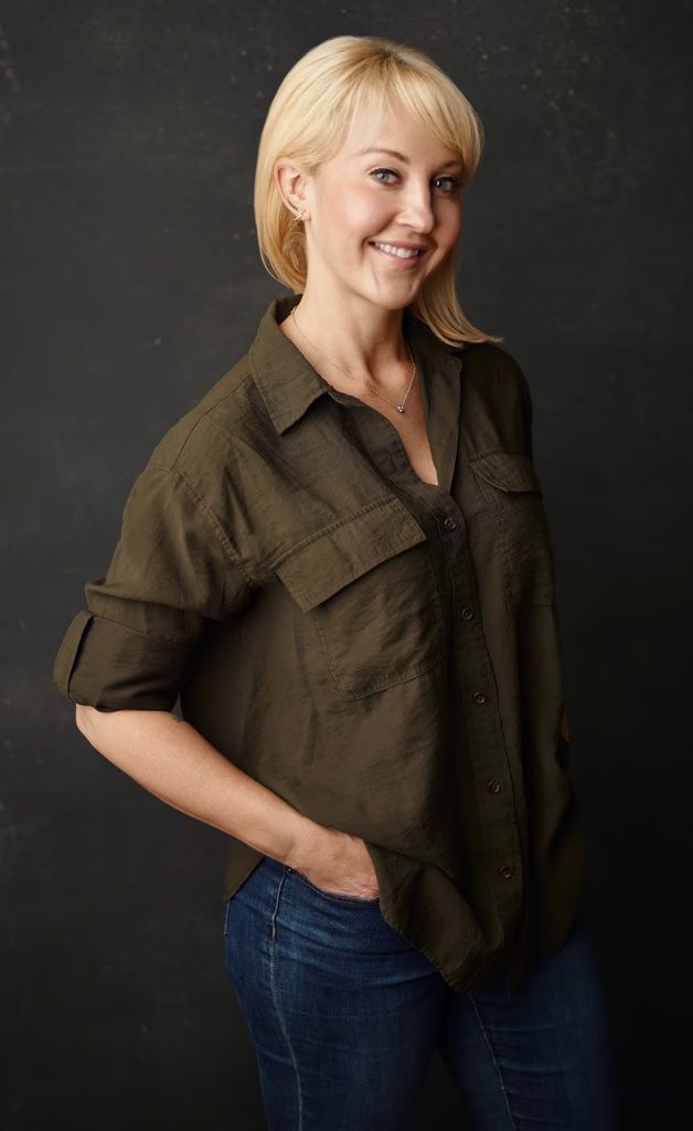 Molly Shelestak, a smiling blonde product leader, wearing a green shirt and jeans, with her hand in her pocket.