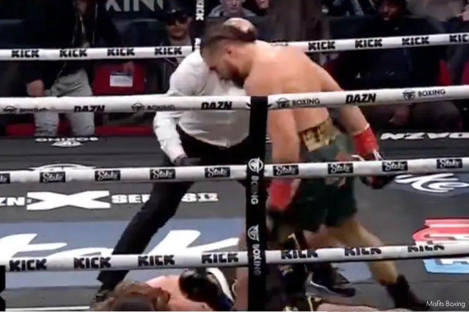 Boxer Tristan Hamm stands over a knocked-down opponent as the referee intervenes during a professional boxing match.